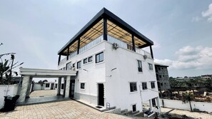 A modern two-story building with a flat roof, large windows, and a covered entrance area.