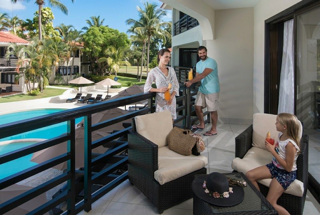 A balcony with wicker furniture, a pool, and a tropical garden.
