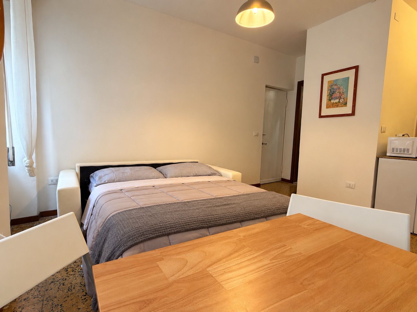 Ein Schlafzimmer mit einem Bett, einem Holztisch und einem weißen Stuhl.