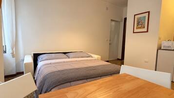 Ein Schlafzimmer mit einem Bett, einem Holztisch und einem weißen Stuhl.