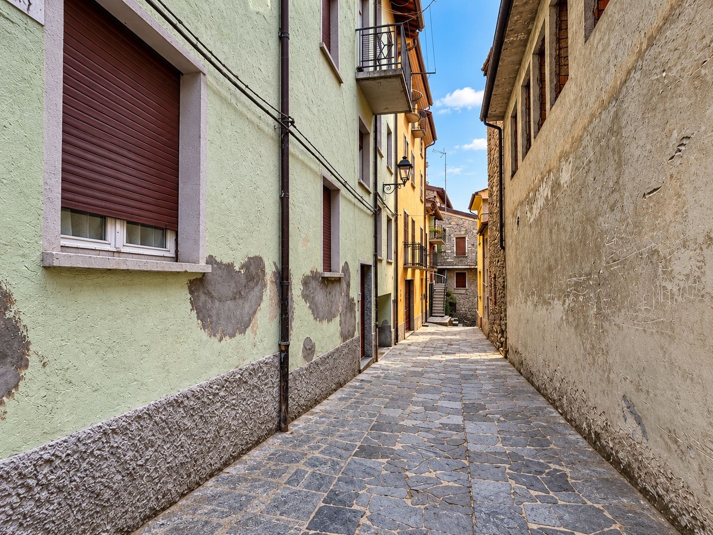 Una estrecha calle adoquinada bordeada por edificios con balcones y ventanas.