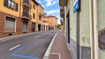 A street with buildings, a sidewalk, and a blue line marking on the road.