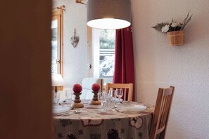 A dining table set with plates, glasses, and a red fruit centerpiece. - Alpine Apartment with Parking - on slopes (Méribel)