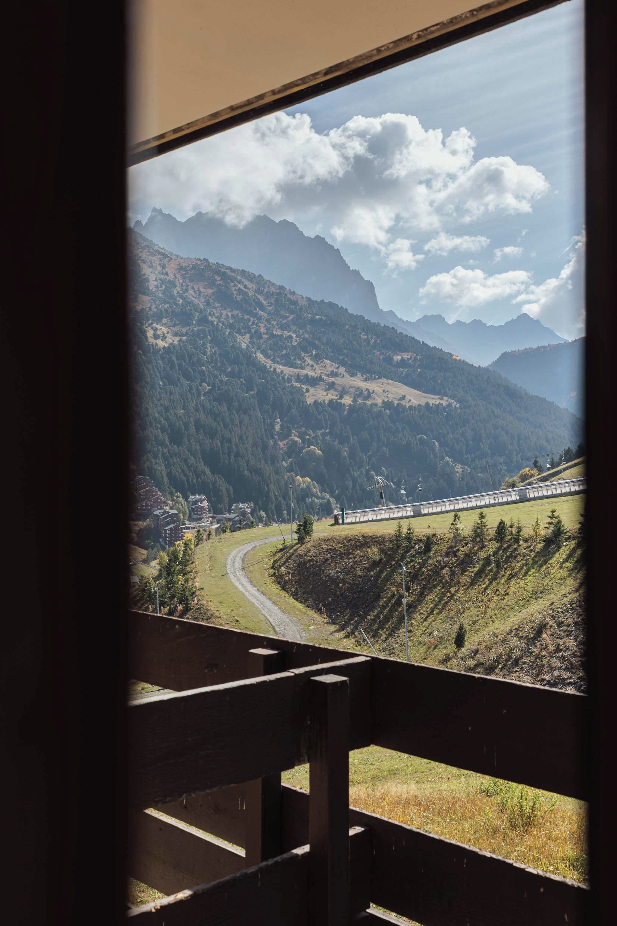 A view of a mountainous landscape with a train track and a wooden fence in the foreground.