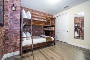 A bunk bed with a wooden frame and white bedding, set against a brick wall with a white door and a mirror reflecting the room. - The best 11-bedroom house with a game room and spa (Kissimmee)