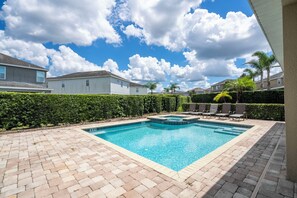 Une piscine rectangulaire dont les bords sont recouverts de carreaux, entourée d’une terrasse en briques.