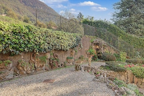 Jardí amb un camí de grava, un mur de pedra i una tanca.