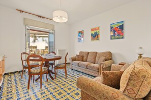 A living room with a dining area, patterned floor, and wall art. - Apartment 'Aurora Alta' with Balcony, Wi-Fi and Air Conditioning (Maslianico)