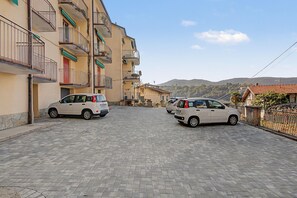 A paved street with two parked cars and multi-story buildings with balconies. - Apartment 'Aurora Alta' with Balcony, Wi-Fi and Air Conditioning (Maslianico)