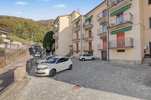Un edifici residencial amb nombroses balcons, una calçada pavimentada i cotxes aparcats.