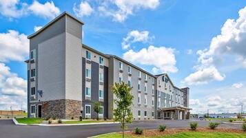 Um hotel de vários andares com design moderno, destacando uma entrada central e área de estacionamento.