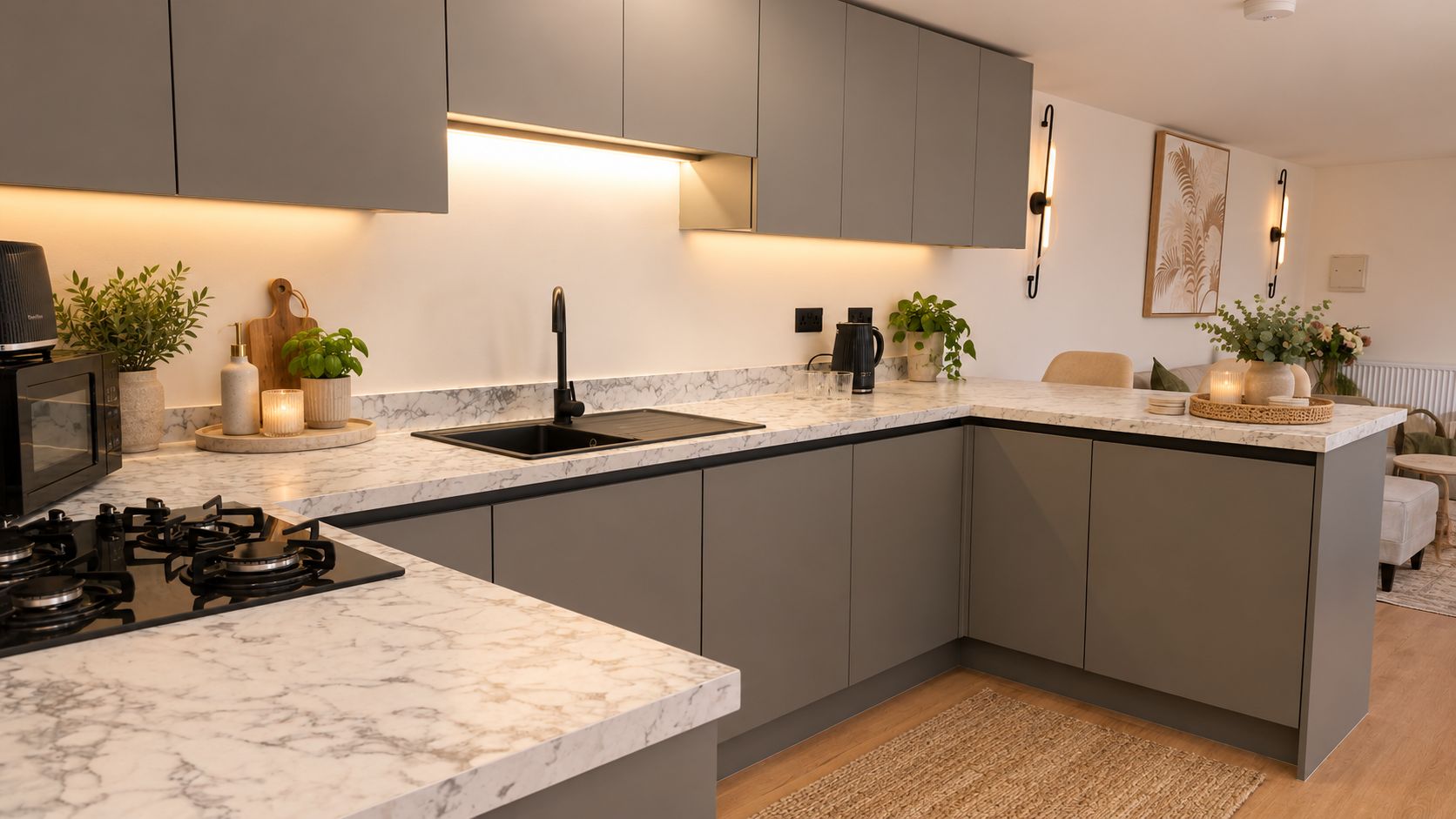 A modern kitchen with grey cabinets, a marble countertop, a gas stove, and a sink.