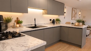 A modern kitchen with grey cabinets, a marble countertop, a gas stove, and a sink. - Stylish 2 BR Flat - Birmingham's Jewellery Quarter
Easy Check In (Birmingham)