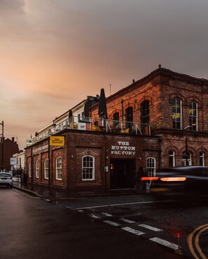 A brick building with a sign reading 'The Button Factory' and a street view with a car passing by. - Stylish 2 BR Flat - Birmingham's Jewellery Quarter
Easy Check In (Birmingham)