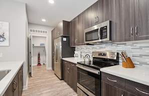 A modern kitchen with dark wood cabinets, stainless steel appliances, and a tiled backsplash. - Lux 2 Bed Desert Ridge 2 Pools Gym 1 Mile to Mayo Clinic Shops Restaurants (Phoenix)
