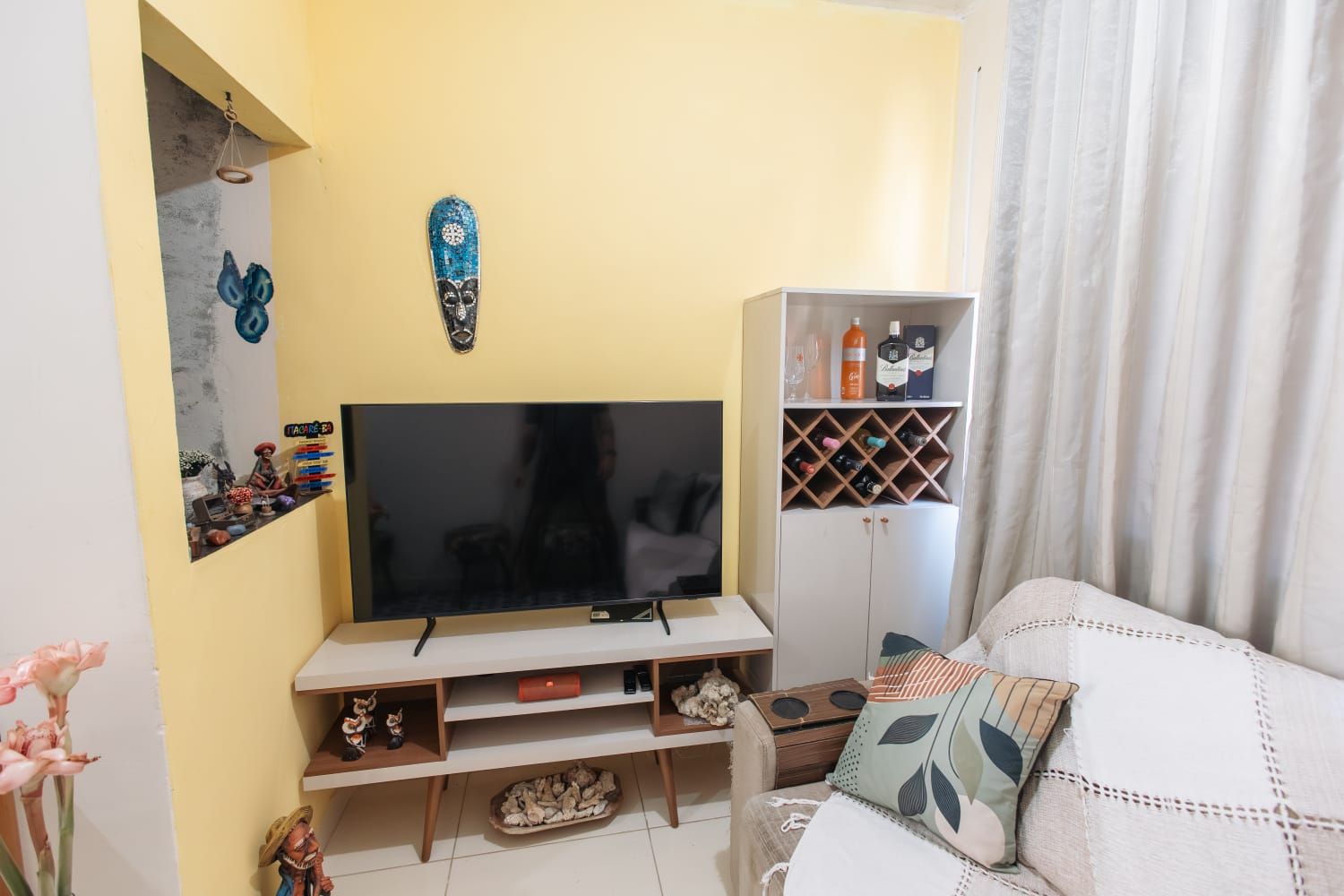Un salon équipé d’un téléviseur à écran plat, d’un meuble de rangement en bois, d’un canapé et d’un porte-bouteilles.