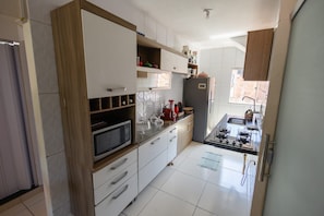 A kitchen with white cabinets, a microwave, a gas stove, and a refrigerator. - Comfortable and peaceful, that's what we call our cozy retreat. (Itacaré)