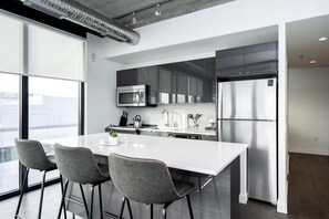 Een moderne keuken met een groot eiland, roestvrijstalen apparatuur en uitzicht op de stad.