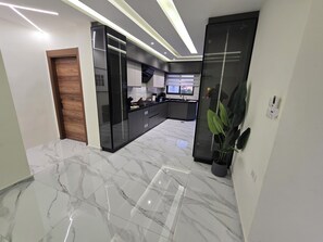 A modern kitchen with a marble floor, black cabinetry, and a built-in oven. - Luxury 3BD with Open View Roof (Amman)