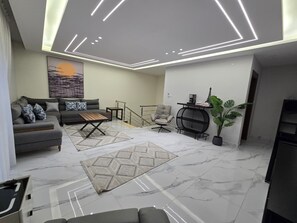 A modern living room with a sofa, armchairs, a coffee table, and a decorative plant. - Luxury 3BD with Open View Roof (Amman)