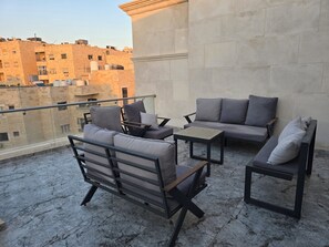 A balcony with outdoor furniture, including a sofa, chairs, and a table. - Luxury 3BD with Open View Roof (Amman)