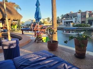 A poolside area with lounge chairs, a palm tree, and a view of a canal with boats. - Awesome studio with AC in the best location in Barra de Navidad (Barra de Navidad)