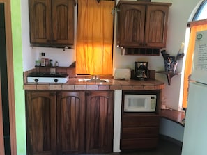A compact kitchen with wooden cabinets, a gas stove, a microwave, and a coffee maker. - Awesome studio with AC in the best location in Barra de Navidad (Barra de Navidad)
