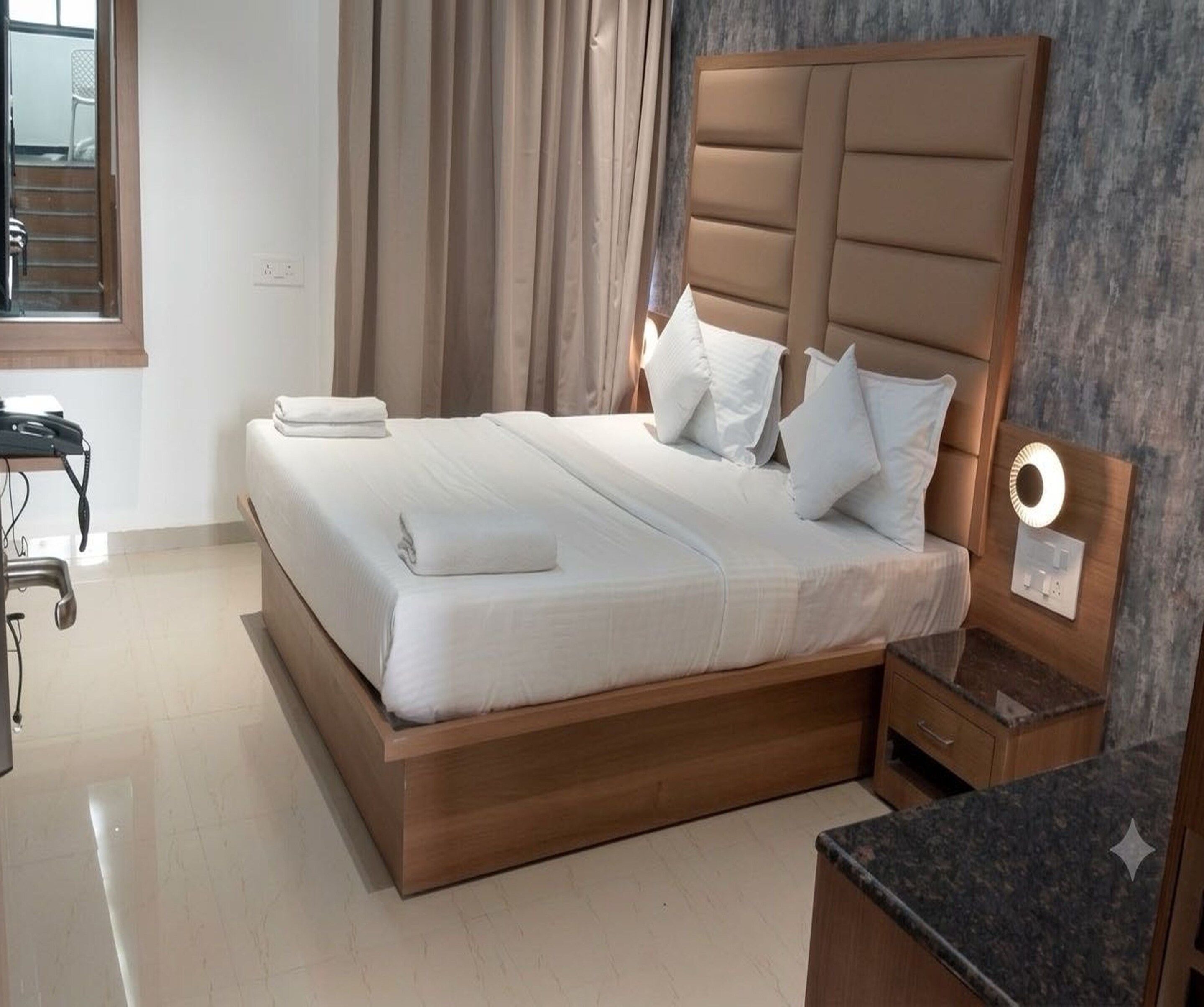 Une chambre d’hôtel avec un lit, une table de chevet et une petite table de nuit avec une lampe.