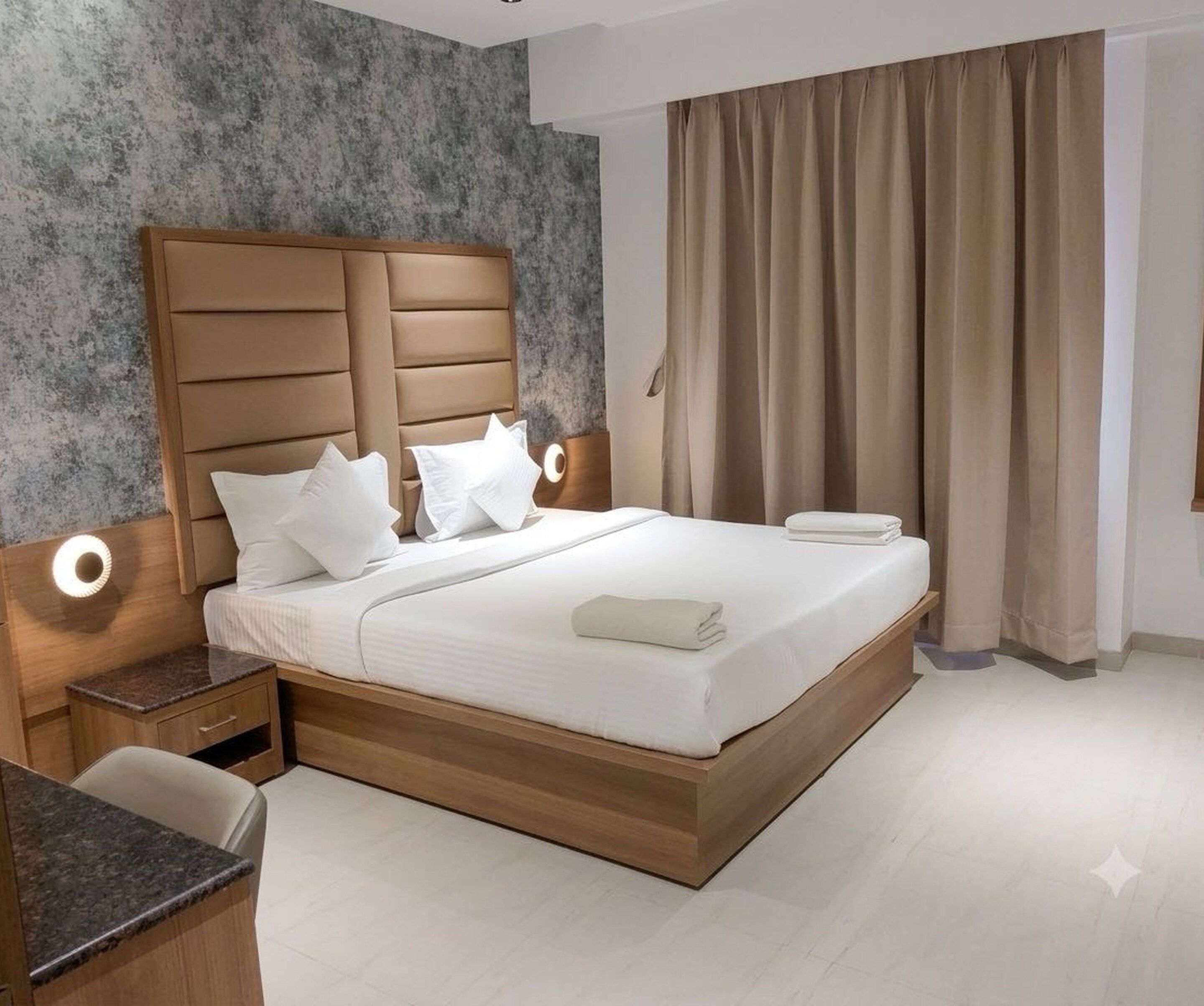 Une chambre d’hôtel moderne avec un grand lit, une tête de lit en bois et une table de chevet avec une lampe.