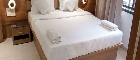A large bed with a wooden headboard, white bedding, and two bedside tables with lamps.