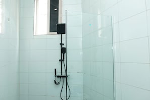 Ein Duschbereich mit Handbrause, Bedienfeld und Glasabtrennung.