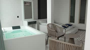 A modern bathroom with a large bathtub, a mirror, a sofa, and a chair.