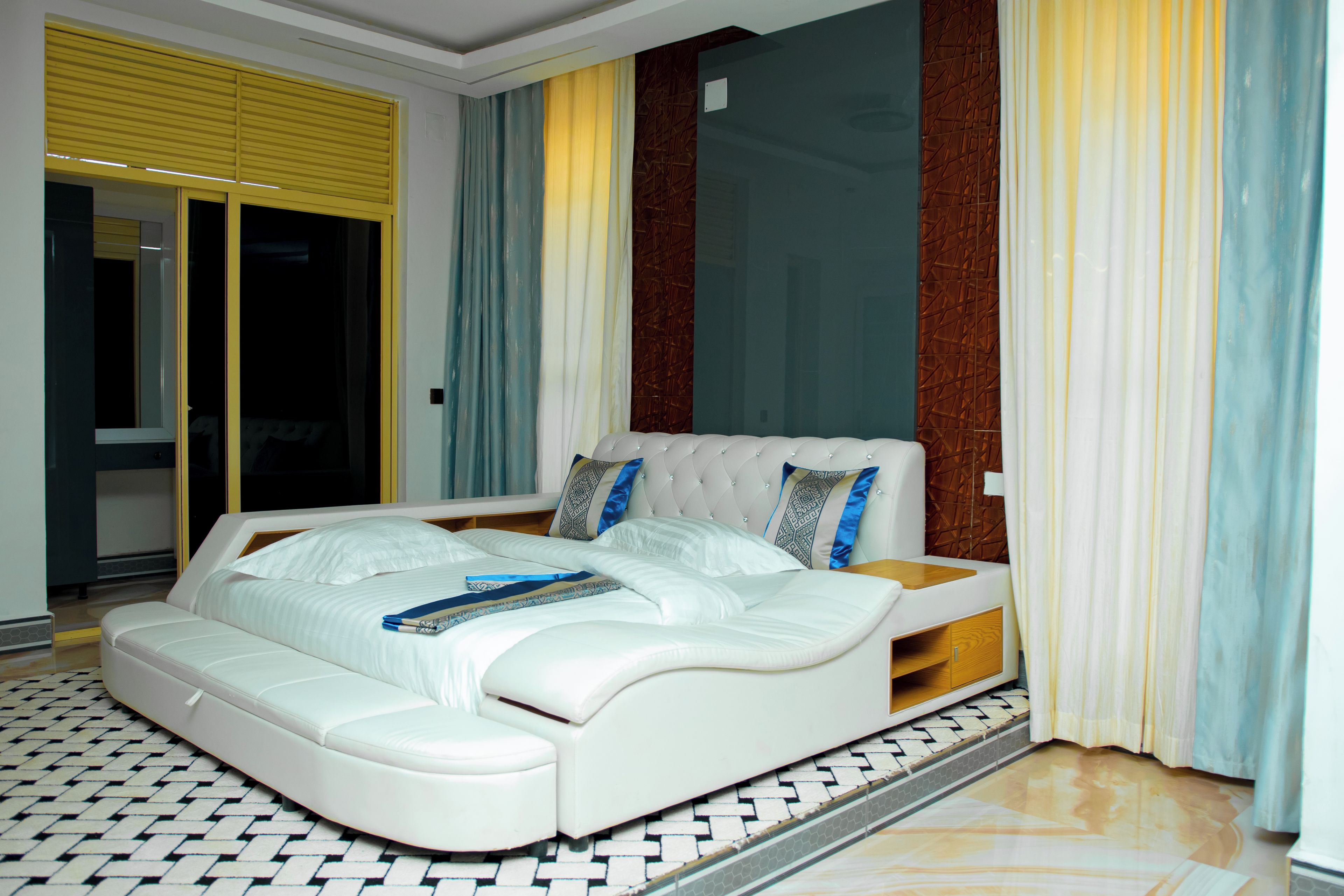 Ein modernes Schlafzimmer mit einem großen Bett, einer eingebauten Sitzbank und einer Schiebeglasdoor.