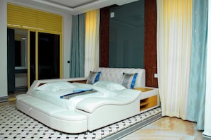 Ein modernes Schlafzimmer mit einem großen Bett, einer eingebauten Sitzbank und einer Schiebeglasdoor.