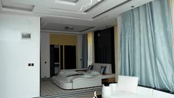 A modern living room with a sofa, a coffee table, and a large window with curtains.