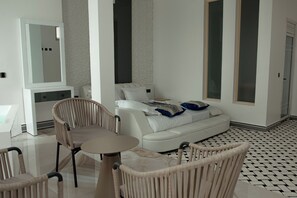 A modern living room with a sofa, two armchairs, a coffee table, and a large mirror. - Neverland Boutique & Suites (Gisenyi)