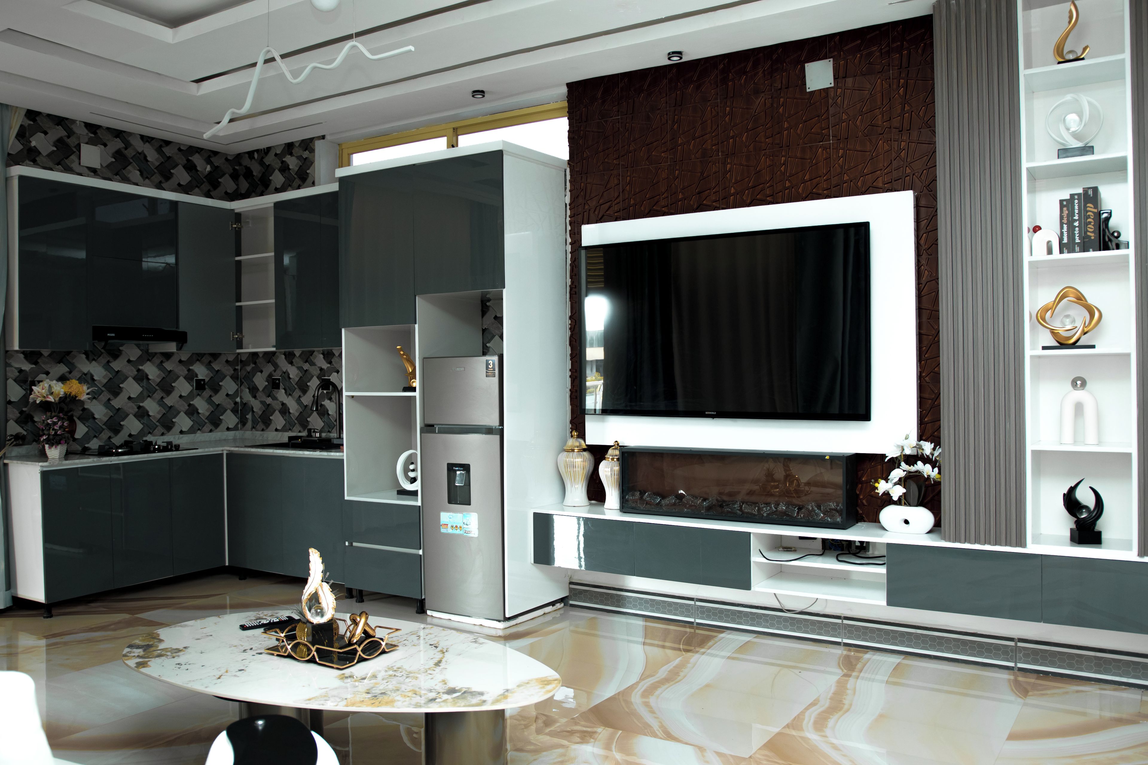 A modern kitchen with a built-in TV, a marble coffee table, and a decorative fireplace.