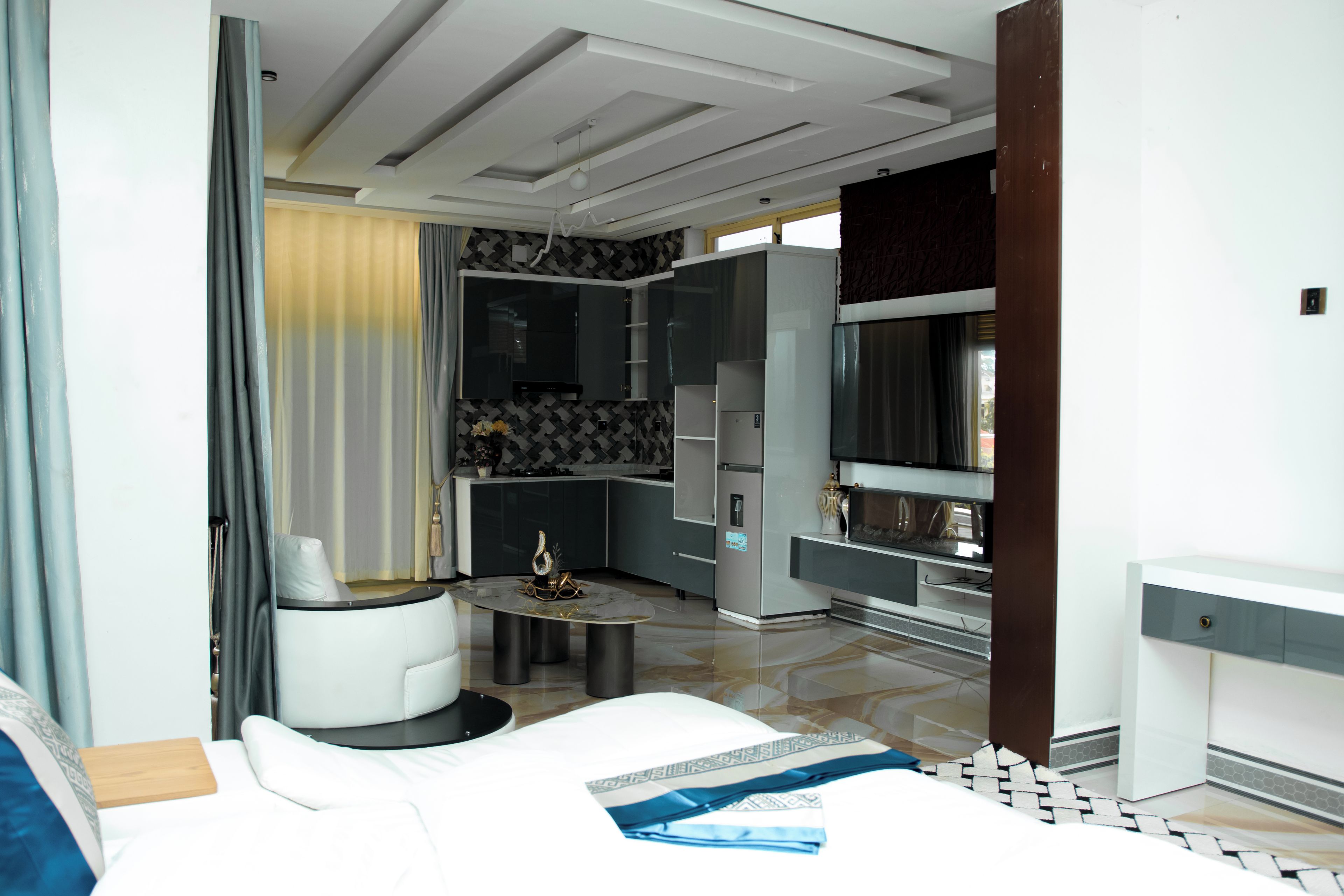 Une chambre d’hôtel moderne comprenant un lit, un petit coin salon, une table à manger et un coin cuisine.
