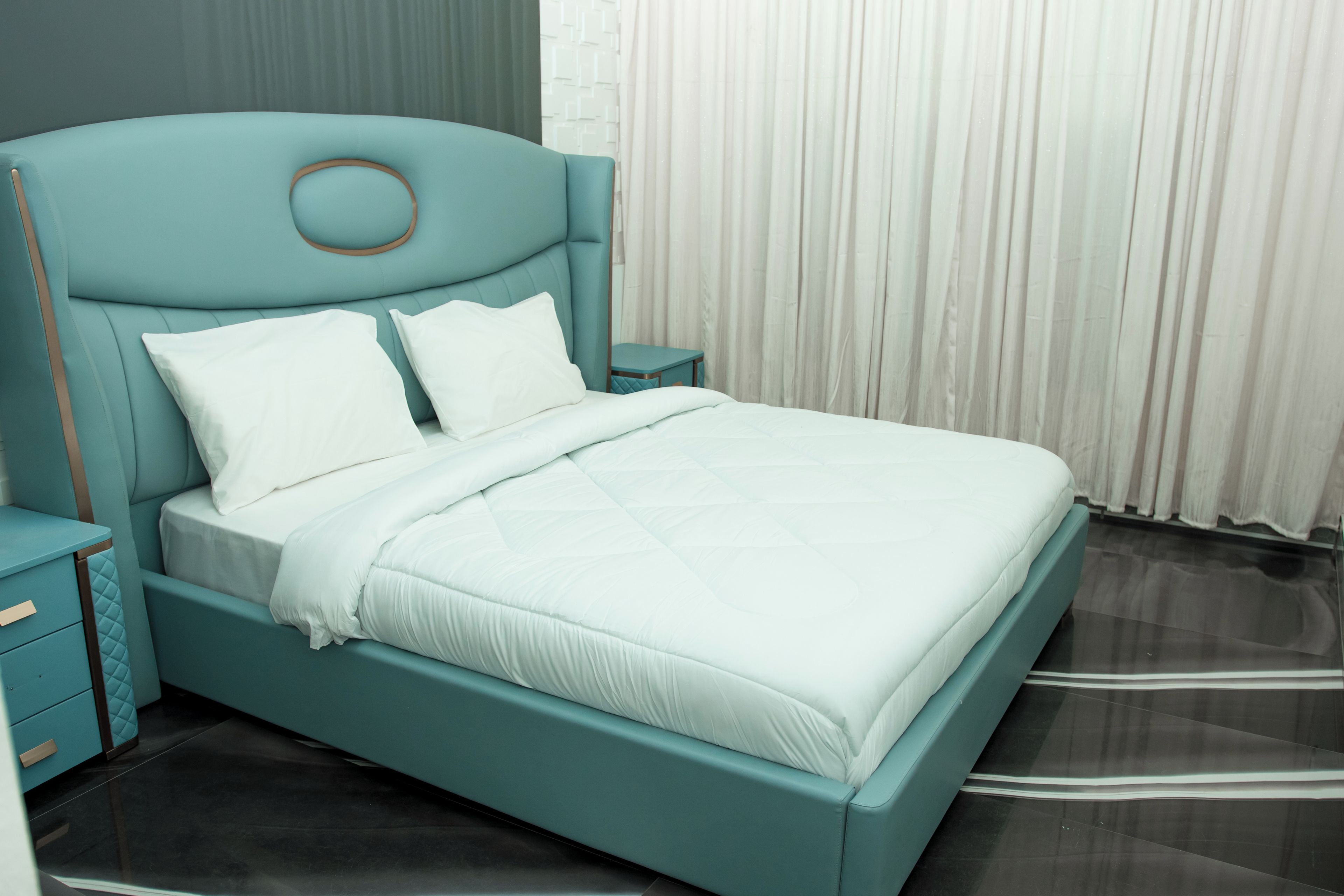 A bed with a headboard, two bedside tables, and a window with curtains.
