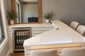 A modern kitchen with a built-in wine cooler, a large island, and two potted plants. - Ocean Beach Studio- Lakefront Escape on Clarklake (clarklake)