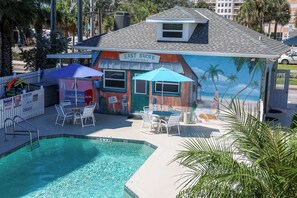 A pool area with a mural of a beach scene, outdoor seating, and a sign for 'East Shore Marina & Bar.'