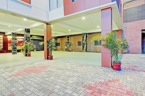 A spacious indoor area with a tiled floor, potted plants, and a closed storefront with signage.