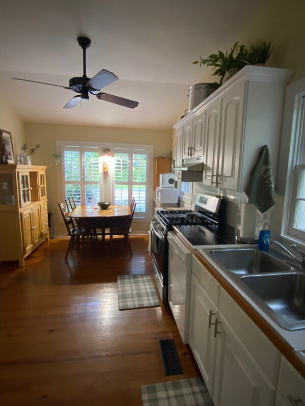 A kitchen with wooden cabinets, a stove, and a ceiling fan.
