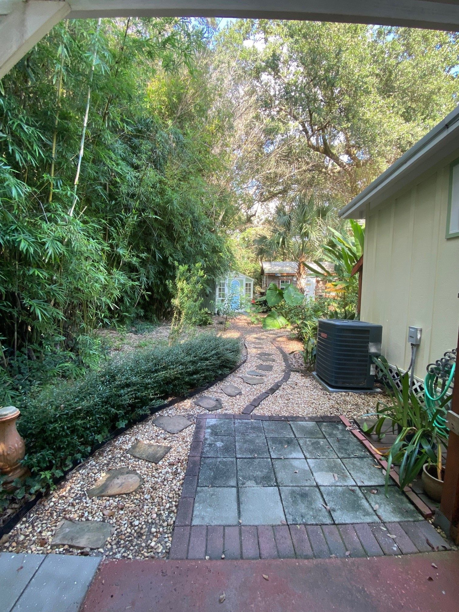 A garden pathway leading to a building with a greenhouse labeled 'GROCERY' and a water feature.
