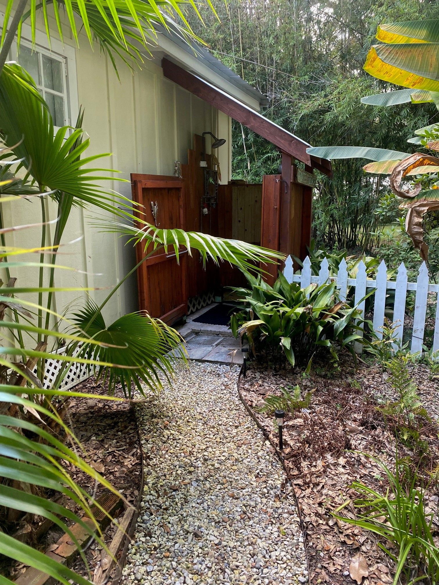 A house with a wooden porch, a white picket fence, and a gravel pathway leading to the entrance.