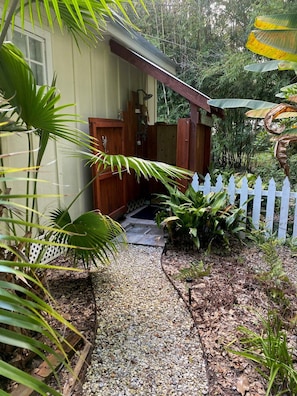 A house with a wooden porch, a white picket fence, and a gravel pathway leading to the entrance. - Cozy 1-bedroom cottage in charming Magnolia Springs with all the amenities (Magnolia Springs)