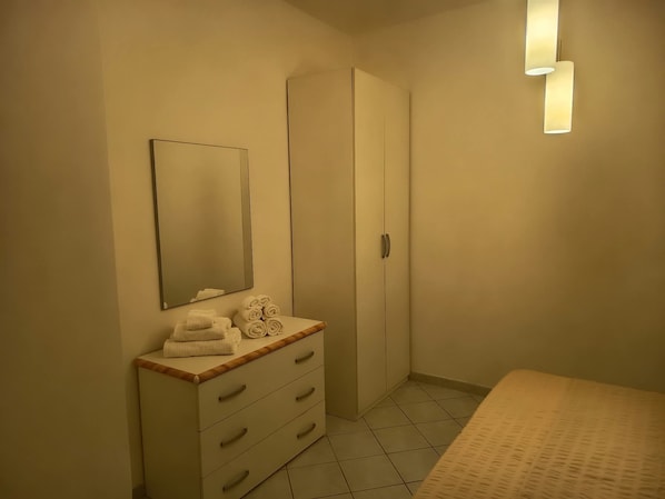 Ein Schlafzimmer mit einem Bett, einer Kommode mit Schubladen, einem Spiegel und einem Kleiderschrank.