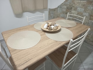 Ein Holztisch mit weißen Stühlen, zwei gewebte Tischsets und ein Teller mit Dekorationen.