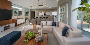 A modern living room with a sectional sofa, a coffee table with decorative items, and a television mounted on the wall. - Sunrise Suites All Inclusive (Puerto Plata)