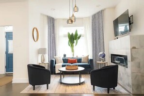 Ein modernes Wohnzimmer mit einer Couch, zwei Sesseln, einem Couchtisch und einem Kamin.